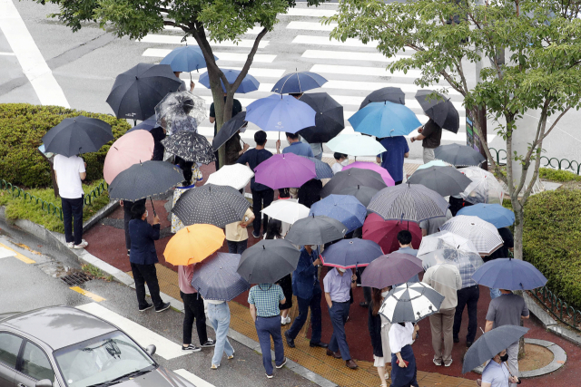 본격적인 장마가 시작된 지난 5일 광주 북구청 교차로 앞 횡단보도를 북구청 직원들이 우산을 쓰고 건너고 있다./광주=연합뉴스