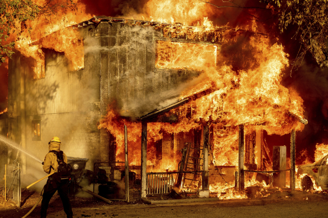 10일(현지 시간) 미국 캘리포니아주 도일 지역의 한 민가가 불길에 휩싸인 가운데 한 소방관이 화재 진압을 위해 물을 분사하고 있다. 지난 2일 캘리포니아주 플루머스 국유림에서 시작된 산불이 폭염과 거센 바람의 영향으로 계속 확산하면서 피해가 커지고 있다. /AP연합뉴스