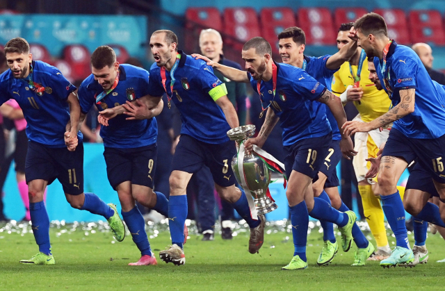 이탈리아 선수들이 12일 유로 2020 우승 뒤 트로피를 들고 원정 관중석 쪽으로 달려가고 있다. 트로피를 든 선수가 수비 핵인 조르조 키엘리니(왼쪽)와 레오나르도 보누치다. /런던=로이터연합뉴스