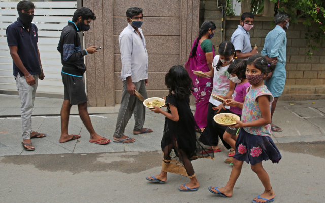지난달 코로나 19의 급속 확산으로 봉쇄된 인도 방갈로 지역에서 어린이들이 무료로 배식 받은 음식을 들고 이동하고 있다. /EPA연합뉴스
