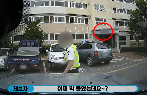 단속하는 경찰관에게 이제 막 안전벨트를 풀었다고 말하는 제보자. 빨간색 동그라미로 표시된 곳이 제보자가 거주하는 아파트 동. /=유튜브 ‘한문철 tv’ 캡처