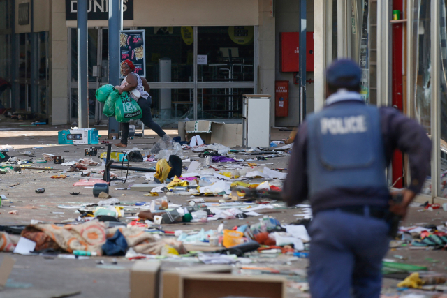 지난12일(현지시간) 남아공 요하네스버그의 한 쇼핑몰에서 약탈자가 경찰을 피해 물건을 훔쳐 달아나고 있다. /AFP연합뉴스