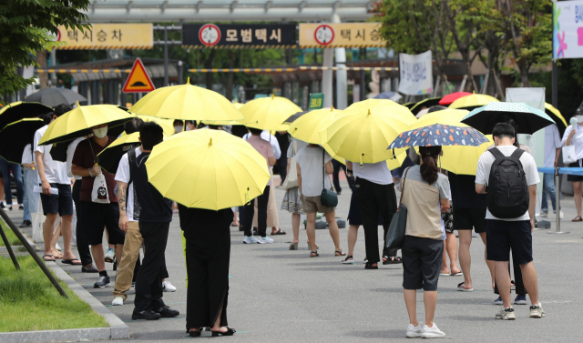 국내 신종 코로나바이러스감염증(코로나19) 신규 확진자 수가 역대 최다를 기록한 14일 오후 서울 서초구 고속버스터미널 광장에 마련된 임시선별검사소 앞에서 서초구가 마련한 양산을 빌려 쓴 시민들이 검사 순서를 기다리고 있다. /연합뉴스