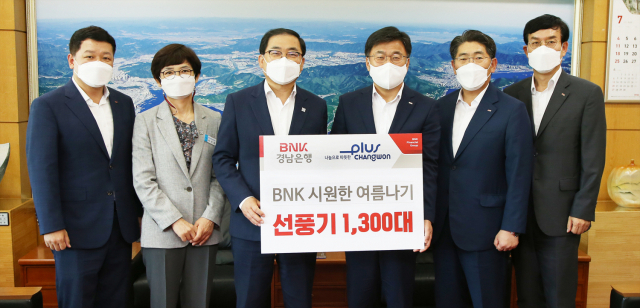 최홍영(오른쪽에서 세번째) BNK경남은행장이 허성무( 〃 네번째) 창원시장에게 ‘BNK 시원한 여름나기 선풍기 기탁 증서’를 전달하고 관계자들과 포즈를 취하고 있다. /사진제공=경남은행