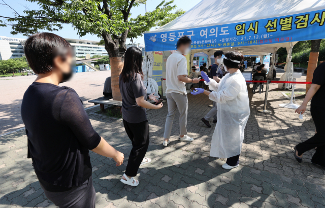 16일 서울 여의도 공원에 마련된 영등포구 임시 선별검사소에서 금융사 직원을 비롯한 시민들이 코로나19 검사를 위한 대기번호표를 받고 있다./연합뉴스