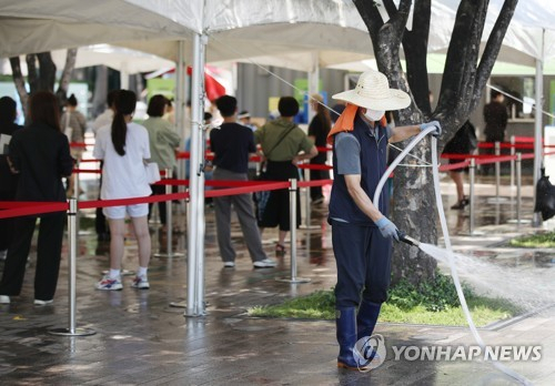 폭염이 이어진 지난 16일 서울광장에 설치된 임시 선별검사소에서 한 작업자가 물을 뿌리며 바닥의 열기를 식히고 있다. /연합뉴스