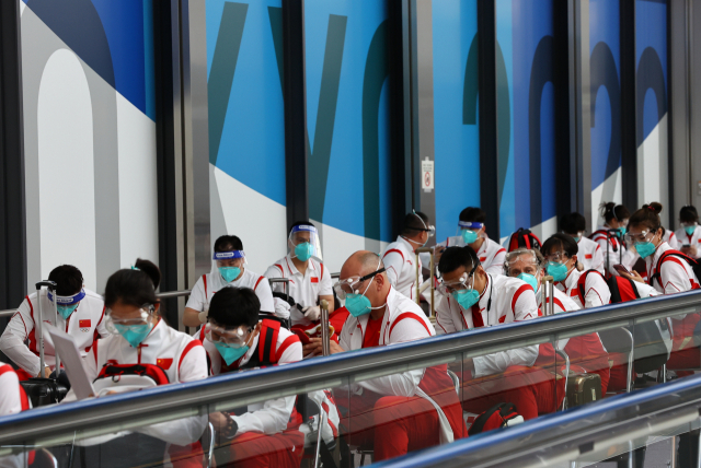 중국 선수단이 19일 나리타 공항에 도착해 마스크와 고글을 쓴 채 입국 수속을 기다리고 있다. /나리타=로이터연합뉴스