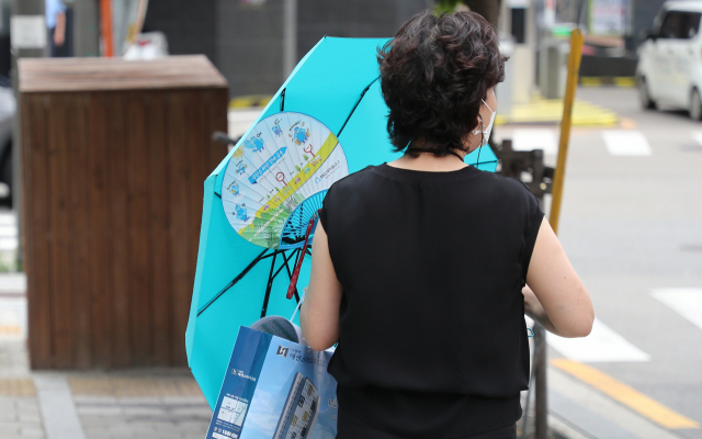 서울에 폭염 경보가 내려진 19일 오후 서울 시내에 소나기가 내리자 우산을 쓴 시민이 발걸음을 재촉하고 있다. /연합뉴스