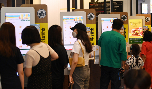 지난 13일 서울 시내 한 패스트푸드 매장에서 소비자들이 키오스크를 이용해 음식을 주문하고 있다./오승현 기자