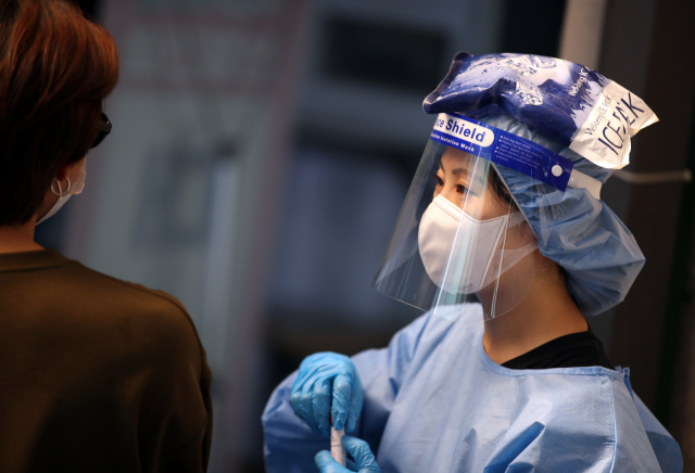 보건소 선별진료소에서 한 의료진이 아이스팩을 머리에 얹고 있다./연합뉴스