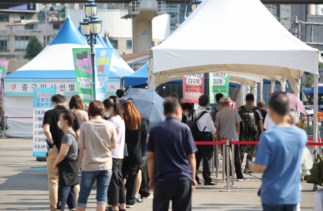 폭염이 이어진 23일 서울역 광장에 마련된 중구 임시 선별검사소에서 시민들이 검사를 받기 위해 뙤약볕 아래 줄을 서 있다. /연합뉴스