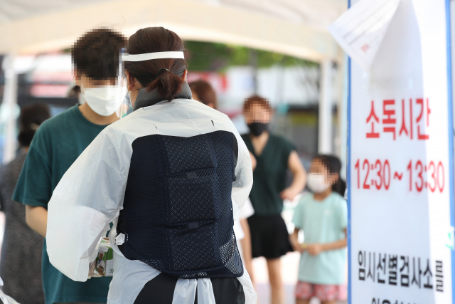 불볕더위가 계속된 23일 서울 면목역 광장 임시선별검사소에서 한 의료진이 아이스팩을 담은 조끼를 입고 있다. /연합뉴스