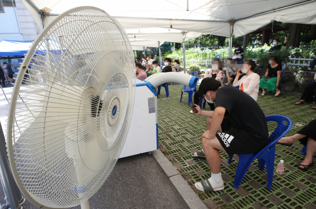 임시선별진료소를 찾은 시민들이 선풍기와 냉풍기 바람을 쐬며 검사 순서를 기다리고 있다./연합뉴스