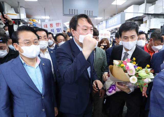 윤석열 전 검찰총장이 27일 오후 부산 중구 자갈치시장을 방문해 상인들의 응원을 듣고 주먹을 치켜올리고 있다. /연합뉴스