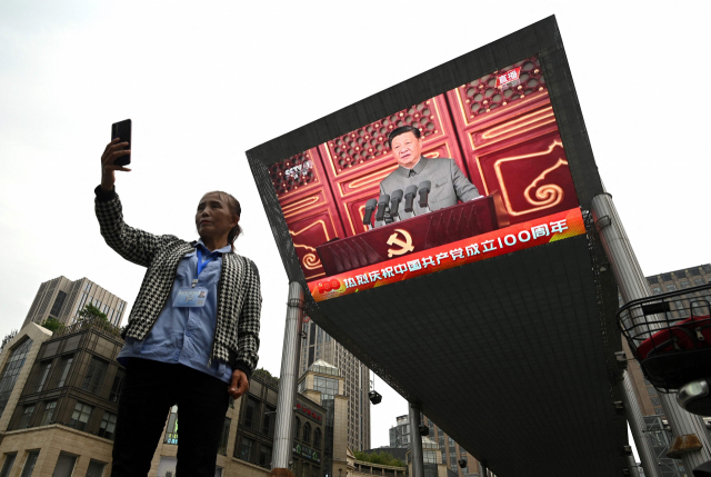 지난 1일 중국 공산당 창당 100주년 기념행사 방송을 배경으로 한 베이징 시민이 기념 셀타를 찍고 있다. /AFP연합뉴스