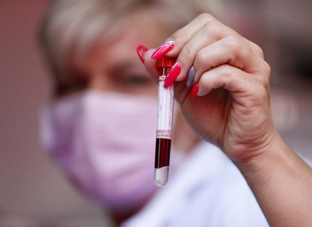 한 여성이 지난 8일 헝가리 부다페스트에서 한 노인으로부터 코로나19 항체 테스트에 사용하기 위해 채취한 혈액을 들어 보이고 있다. /부다페스트=AP연합뉴스