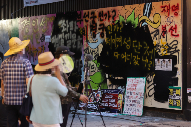 서울 종로구 관철동의 한 중고서점 앞에 윤석열 전 검찰총장 아내 김건희 씨를 비방하는 내용의 벽화가 게시돼 논란이 이어지는 가운데 한 유튜버가 벽화 위에 검은색 페인트로 덧칠했다. 사진은 31일 검은색 페인트로 덧칠된 벽화./연합뉴스