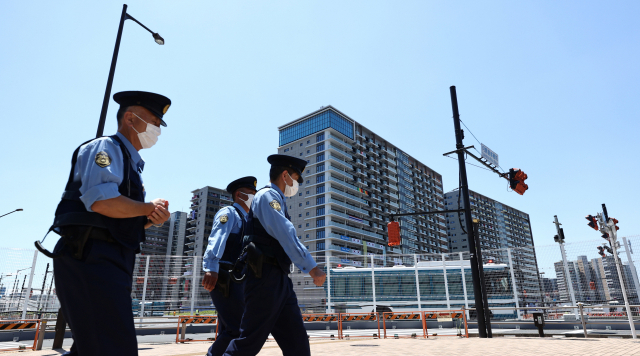 지난달 22일 오전 도쿄 하루미 지역 올림픽선수촌 앞을 경찰관들이 지나가고 있다./연합뉴스