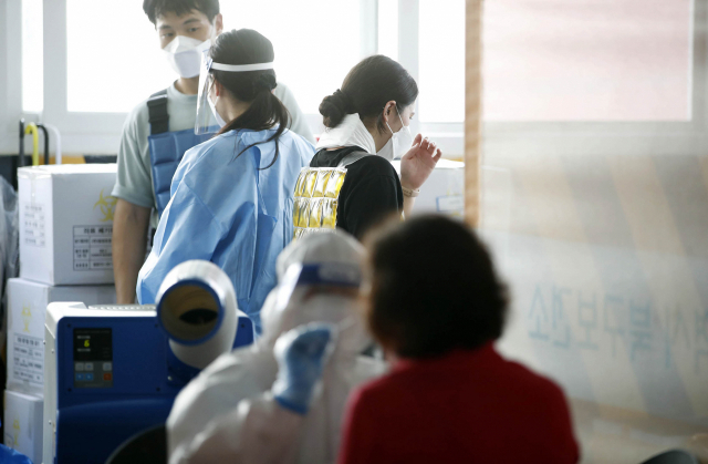 선별진료소에서 보건소 의료진들이 폭염 속에 냉조끼를 착용하고 일하고 있다./연합뉴스