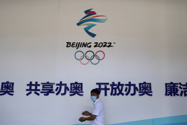 2022 베이징 동계올림픽 안내판 앞으로 마스크를 쓴 사람이 지나가고 있다. /로이터연합뉴스