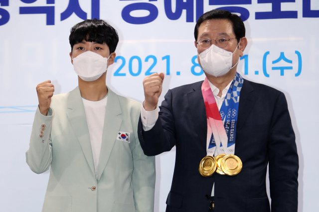 11일 광주시청 소회의실에서 2020 도쿄올림픽 양궁 3관왕에 오른 안산(왼쪽) 선수가 이용섭 광주시장에게 금메달을 걸어준 뒤 기념 촬영을 하고 있다. 안산은 광주시 명예홍보대사에 위촉됐다. /연합뉴스