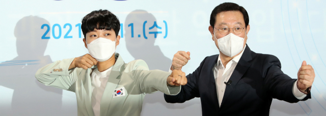 11일 광주시청 소회의실에서 2020 도쿄올림픽 양궁 3관왕에 오른 안산(왼쪽) 선수와 이용섭 광주시장이 여자 양궁 단체전 금메달 수상 당시 '활시위 세리머니'를 재연하고 있다. /연합뉴스