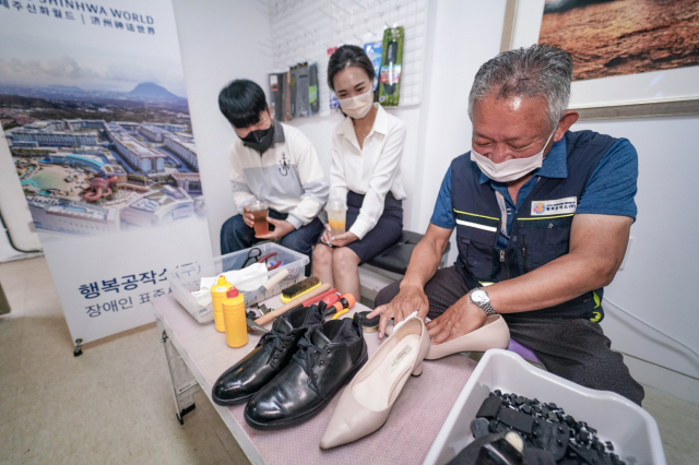 행복구두수선카페를 찾은 손님들이 구두수선 서비스를 받고 있다./사진제공=제주신화월드