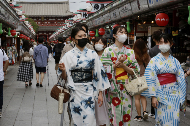 13일 일본 도쿄의 한 거리에서 전통의상을 입은 여성들이 마스크를 쓰고 한 쇼핑 거리를 걷고 있다. /AP연합뉴스