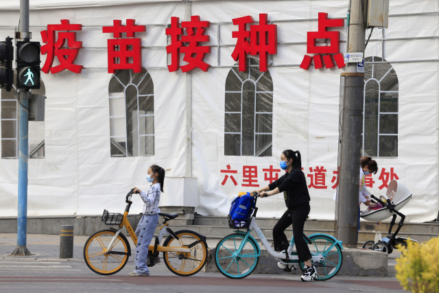 중국 수도 베이징의 한 백신 접종소 인근 거리에서 6월 11일 자전거를 탄 여자 어린이가 횡단보도 앞에 서 있다. /AP연합뉴스
