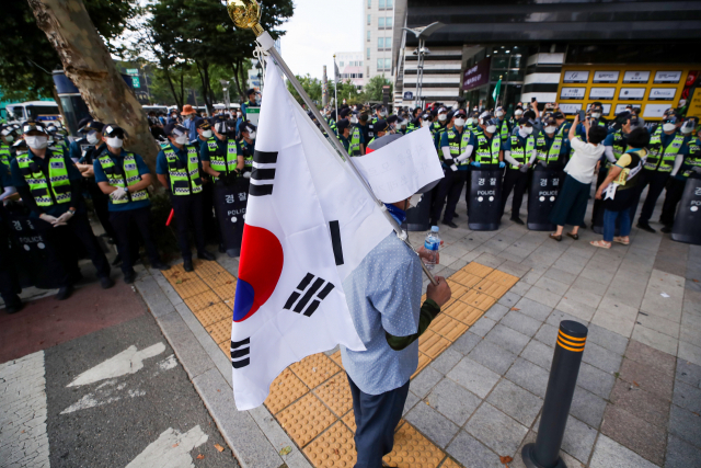 15일 오후 국민혁명당의 기자회견이 열린 서울 종로구 주얼리시티 인근에서 태극기를 든 시민이 접근을 통제하는 경찰 앞에 서 있다./연합뉴스
