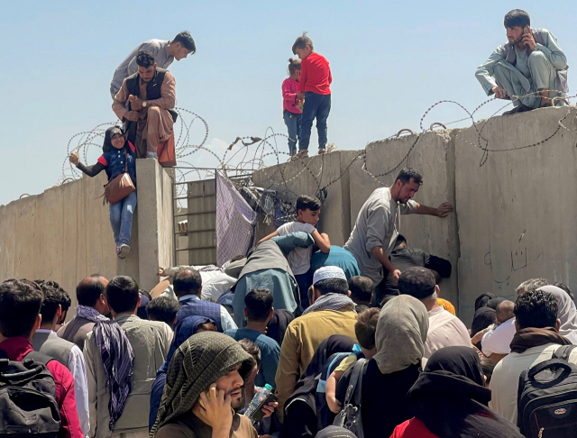 16일(현지 시간) 아프가니스탄을 떠나기 위해 카불국제공항 앞으로 몰려든 사람들이 어린 아이들을 담장 위로 올려 공항 안으로 들여보내고 있다./로이터연합뉴스