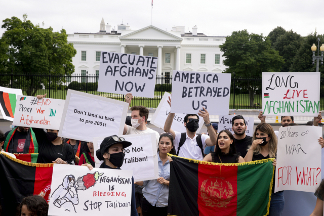 15일(현지 시간) 미국 백악관 앞에서 탈레반의 아프간 장악에 반대하는 사람들이 ‘미국이 우리를 배신했다’ 등의 문구가 쓰인 팻말과 아프간 국기를 들고 시위를 벌이고 있다./EPA연합뉴스