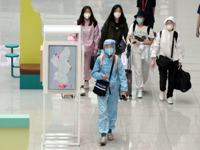 20일 오후 영종도 인천국제공항 제1여객터미널 출국장 보세구역에서 방역복과 고글로 중무장한 해외 출국자가 면세점 앞을 지나고 있다./연합뉴스