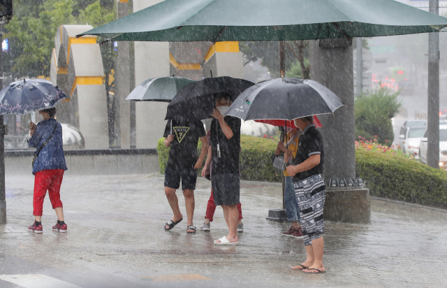 전국적으로 폭우가 내린 21일 오전 서울 양천구의 한 횡단보도 앞에서 우산을 쓴 시민들이 서 있다. /연합뉴스