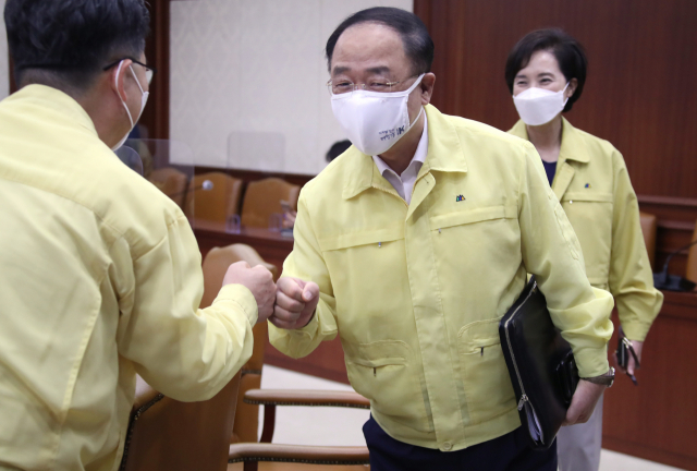 홍남기 부총리 겸 기획재정부 장관(가운데)이 자가격리를 마치고 20일 정부서울청사에서 열린 코로나19 대응 중앙재난안전대책본부 회의에 참석해 관계자와 인사하고 있다. /연합뉴스