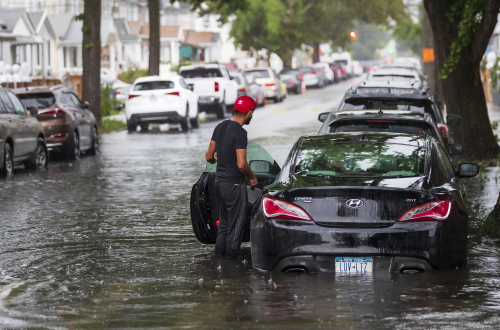 22일(현지시간) 허리케인 헨리가 동반한 폭우로 침수된 미국 뉴욕시 퀸즈 지구의 도로에서 한 운전자가 차량을 살피고 있다. /EPA연합뉴스