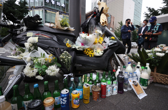 27일 오후 서울 강남구 선릉역 인근 도로에 전날 사망한 오토바이 배달원을 추모하는 국화꽃 등이 놓여져 있다./ 연합뉴스