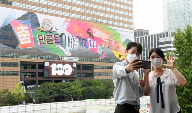 30일 서울 종로구 세종문화회관에서 교보 직원들이 교보빌딩에 100번째 광화문 글판 게시를 기념해 글판을 배경으로 기념촬영을 하고 있다. 100번째 광화문 글판은 BTS의 노래 '퍼미션 투 댄스'의 '[춤]만큼은 마음 가는 대로, 허락은 필요 없어'라는 노랫말을 인용했다. 디자인에는 미디어 아티스트인 이예승 작가가 참여했다./권욱 기자 2021.08.30