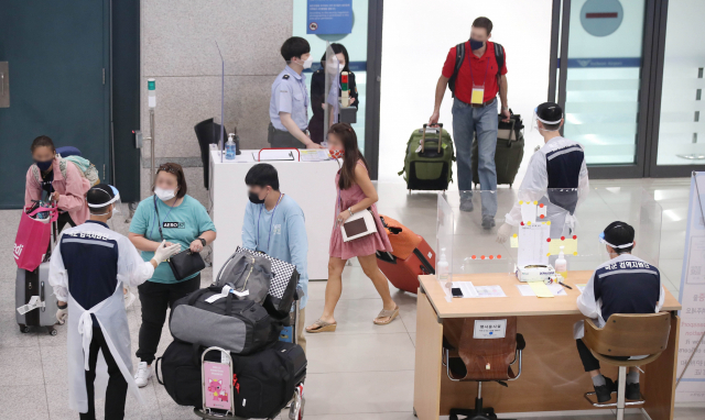 7월 1일 인천국제공항 제1여객터미널 입국장에서 입국자들이 방역 관계자의 안내를 받고 있다. /연합뉴스