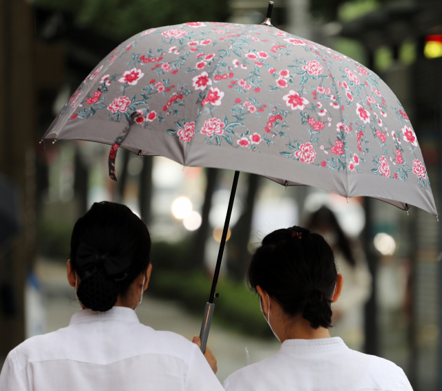 지난달 31일 오전 서울 시내에서 시민들이 꽃 우산을 쓰고 걸어가고 있다. /연합뉴스