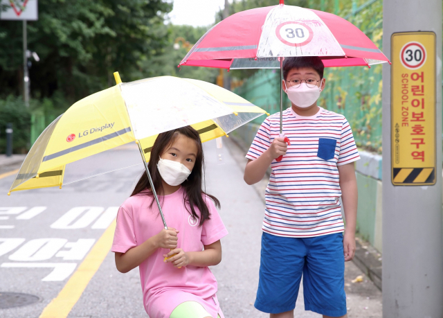 어린이들이 LG디스플레이가 마련한 '투명 안전 우산'을 쓰고 길을 걸어가고 있다./사진제공=LG디스플레이