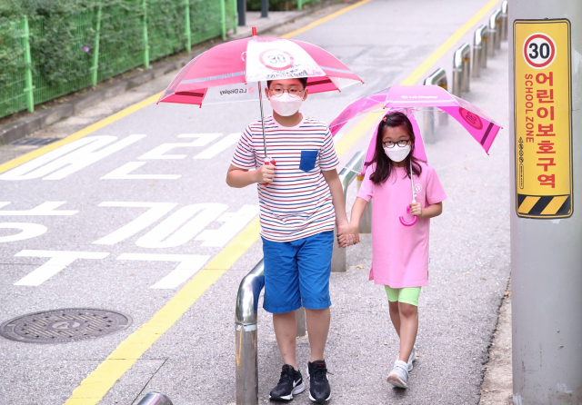 어린이들이 LG디스플레이가 마련한 '투명 안전 우산'을 쓰고 길을 걸어가고 있다./사진제공=LG디스플레이