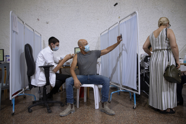 이스라엘 라마트간 지역에 마련된 신종 코로나바이러스 감염증(코로나19) 백신 접종소에서 지난달 30일(현지시간) 한 남성이 화이자 백신을 접종받으면서 셀카를 찍고 있다. /AP연합뉴스