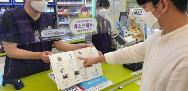 편의점 CU 점포에서 고객이 재난지원금으로 구매할 수 있는 전자제품 카탈로그를 살펴보고 있다./사진 제공=CU