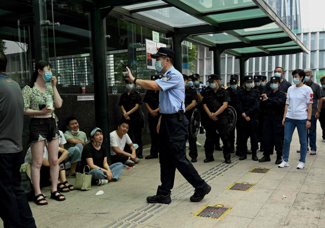 15일 중국 선전의 헝다그룹 본사 앞에 돈을 돌려달라는 투자자들이 몰려든 가운데 한 경찰관이 질서 유지를 당부하고 있다 / AFP연합뉴스