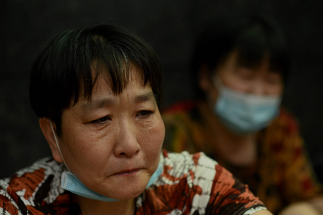 지나 16일 파산 위기에 몰린 중국의 대형 민간 부동산 개발업체 헝다 그룹의 광둥성 선전 본사 앞에 투자자들이 항의하기 위해 모인 가운데 한 여성이 울상을 짓고 있다. /연합뉴스