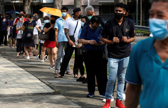 싱가포르가 신종 코로나바이러스 감염증(코로나19) 확산으로 비상인 가운데 21일(현지시간) 주민들이 코로나19 신속 검사를 받기 위해 검사소 앞에 길게 줄지어 서 있다. /로이터연합뉴스