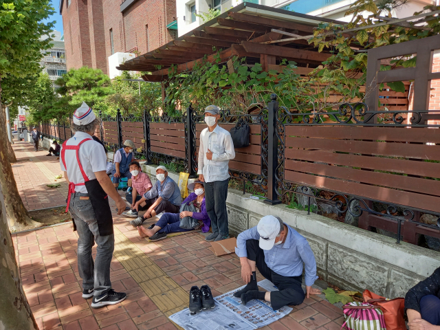 김하종(왼쪽) 신부가 건물 앞에서 도시락을 기다리고 있는 노숙자·독거노인들과 얘기를 나누고 있다.