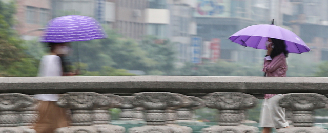 늦여름 비가 내린 지난달 31일 오후 서울 중구 청계천 모전교를 쓴 시민들이 지나가고 있다./연합뉴스