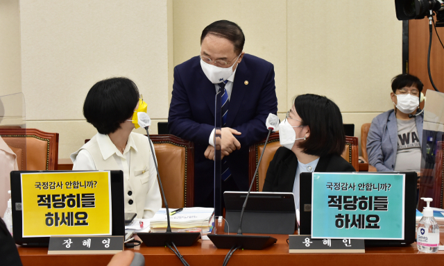 홍남기 경제부총리가 5일 서울 여의도 국회에서 열린 기획재정위원회의 기획재정부 국정감사에 출석해 정의당 장혜영 의원, 기본소득당 용혜인 의원과 대화를 나누고 있다. /연합뉴스